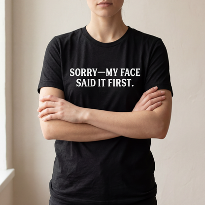 Model wearing a black t-shirt with white text that reads “SORRY—MY FACE SAID IT FIRST