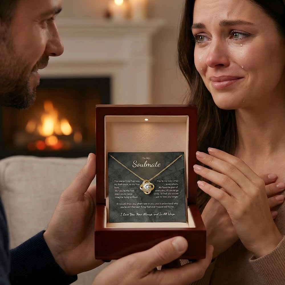 Man presenting a necklace to a woman in a warm indoor setting with a fireplace.